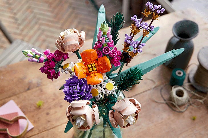 A flower bouquet made from lego featuring a range of blooms in different colours and leaves.